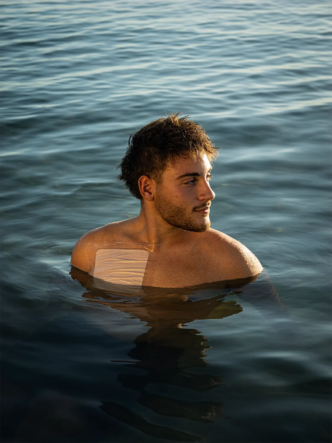 Ragazzo in mare al tramonto con CVCover Waterproof sul petto